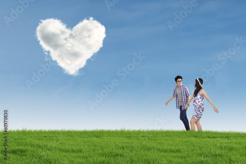 Romantic couple with heart shaped cloud in nature