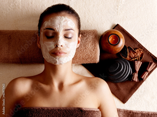 woman relaxing with facial mask on face at beauty salon photo