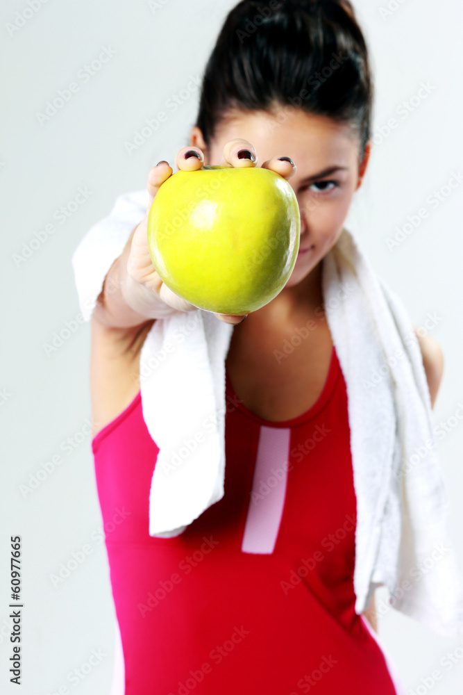 Young sport woman holding apple on gray background Young sport woman holding apple on gray background