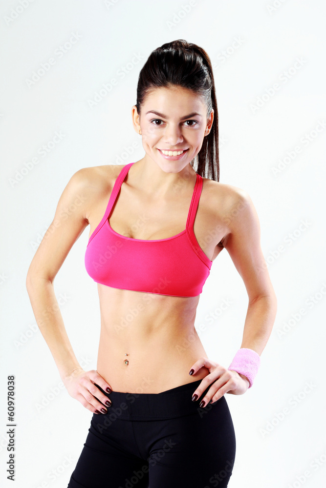 Portrait of a young smiling sport woman on gray background