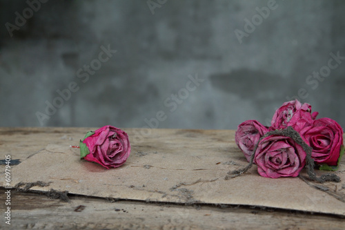 Vintage old paper pink roses  on grunge wood table with selectiv photo