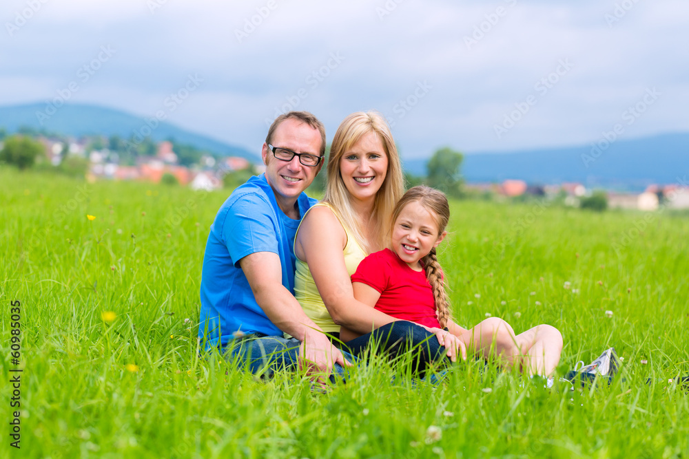 Glückliche Familie sitzt auf Wiese im Sommer Glückliche Familie sitzt auf Wiese im Sommer