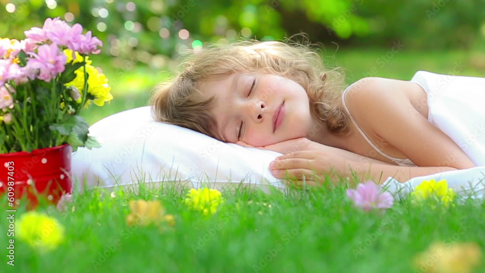 Happy child sleeping on green grass outdoors in spring garden Happy child sleeping on green grass outdoors in spring garden