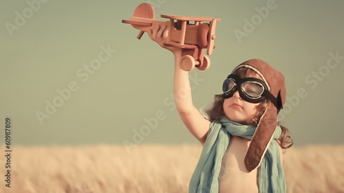 Happy kid playing with toy airplane against summer sky