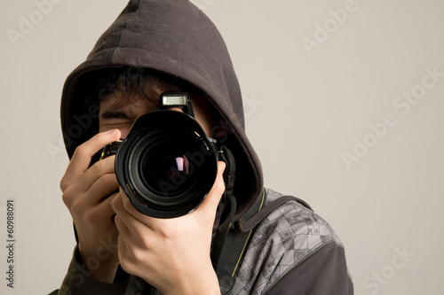 A young man in a hood using a professional camera