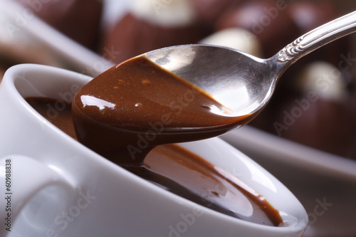 Spoon with liquid chocolate and cup closeup horizontal. macro