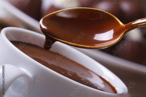 Liquid chocolate dripping from the spoon in a cup