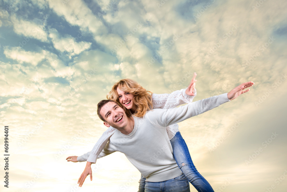 Man giving piggyback ride to girlfriend under the sky Man giving piggyback ride to girlfriend under the sky