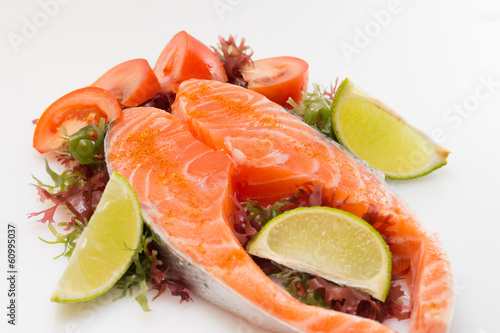 Raw salmon fillet with vegetables on white background