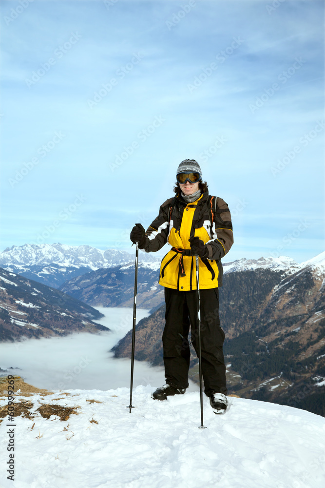 The skier stands on mountain summit against heavy fog