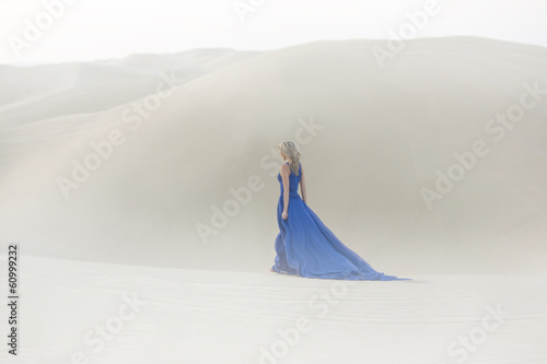 Beautiful young woman walks in desert  long  blue dress