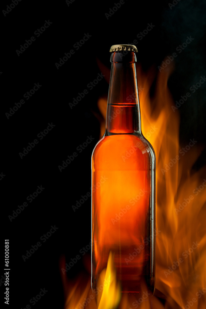 Beer bottle in fire on black