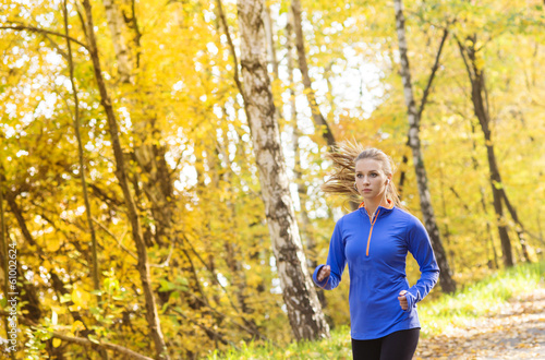 Active and sporty woman runner in autumn nature
