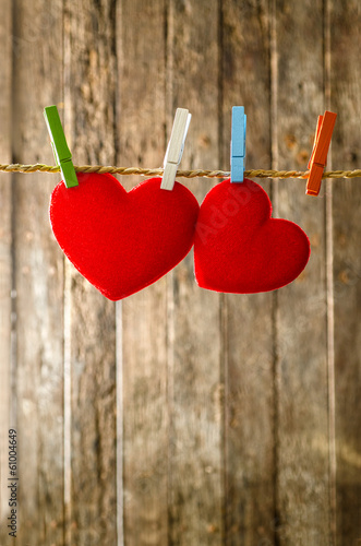 two red heart hanging on the clotheslinen old wood background. photo