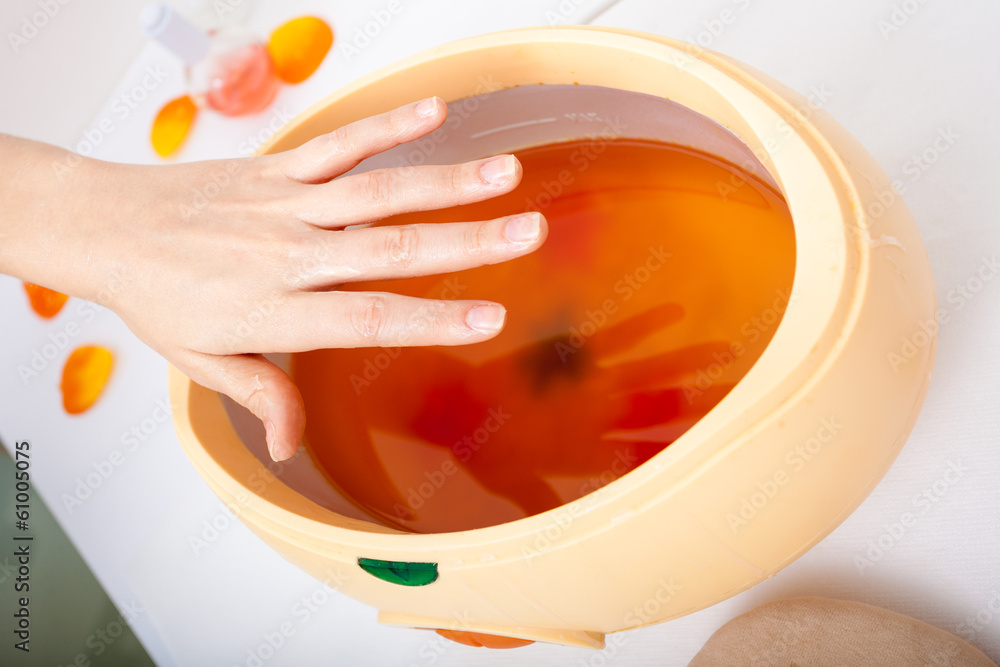 Ταπετσαρία Female hand and orange paraffin wax bowl. Woman in beauty salon