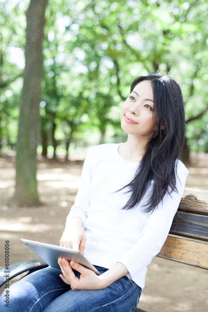 公園のベンチでタブレットPCを使う女性 公園のベンチでタブレットPCを使う女性