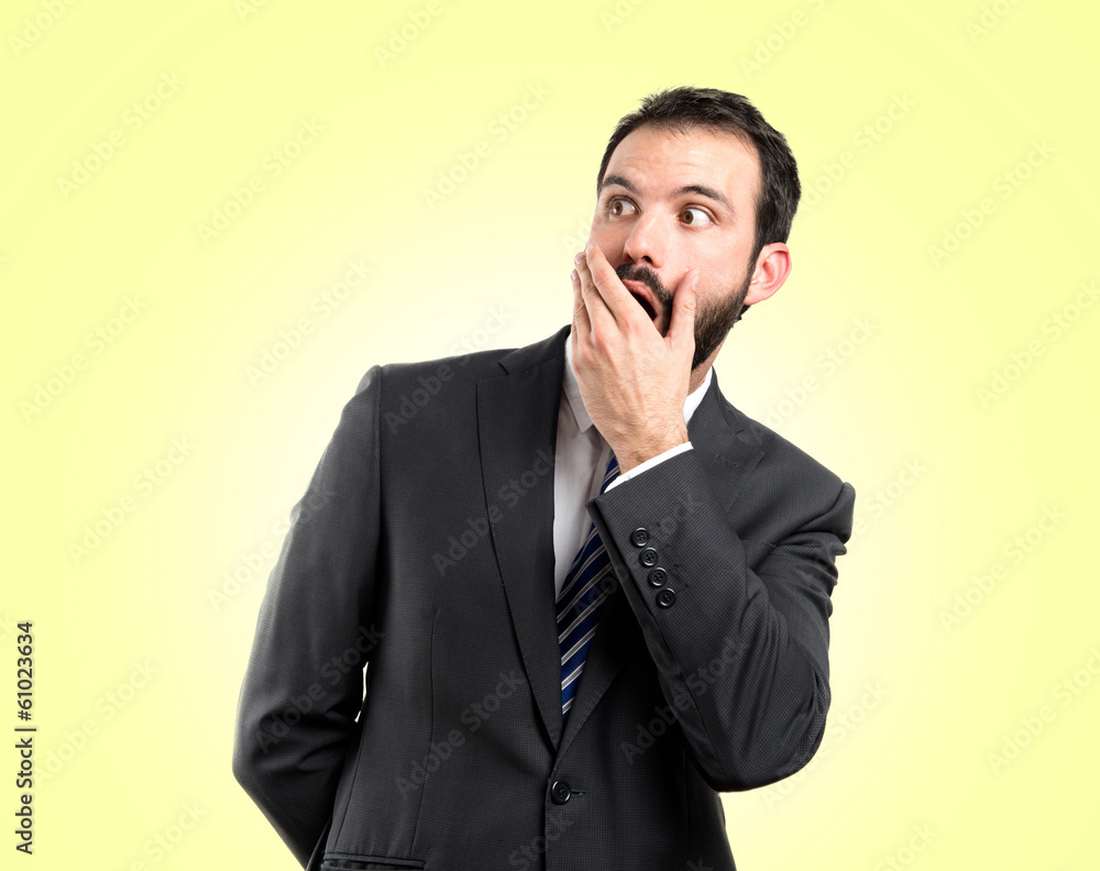 Businessman surprised over yellow background Businessman surprised over yellow background