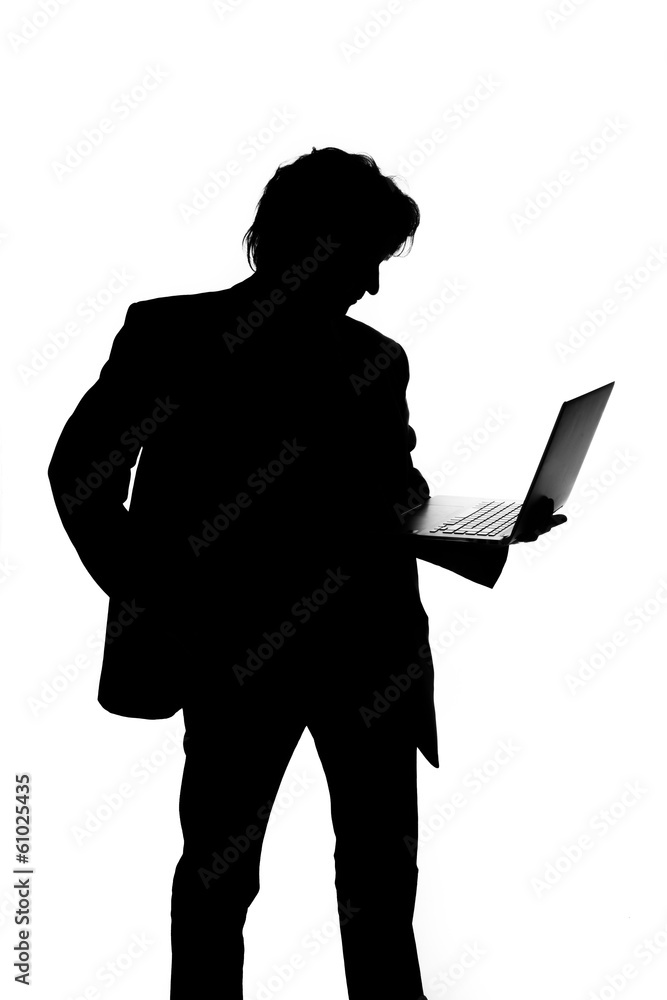 Silhouette of a man in suit holding laptop