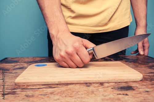 Young man with knife and chopping board