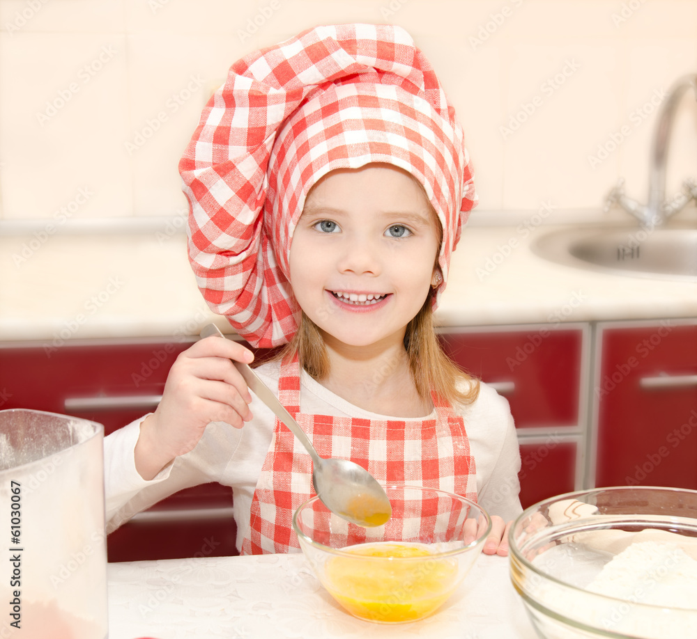 Smiling little girl with chef hat stirrring cookie dough Smiling little girl with chef hat stirrring cookie dough