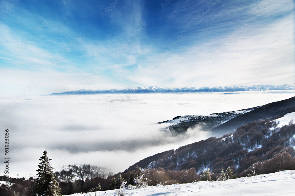Winter landscape, snowy mountain peaks and low clouds