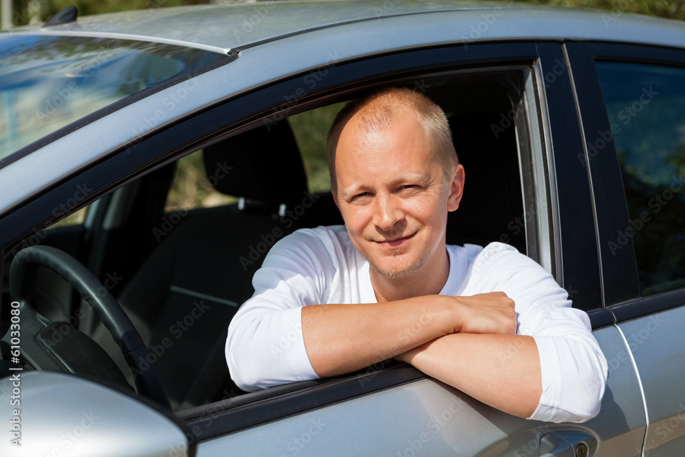 junger erwachsener mann im neuen auto mit schlüssel lachend junger erwachsener mann im neuen auto mit schlüssel lachend