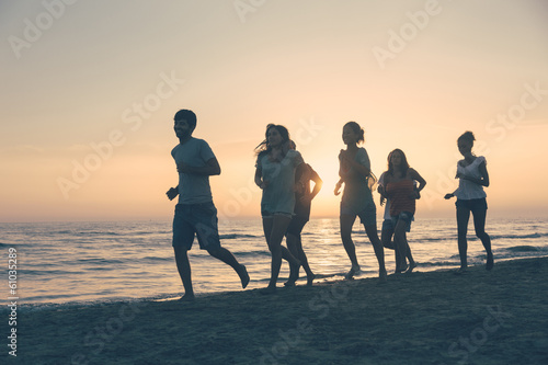 Group of People Running on the Beach at Sunset © william87