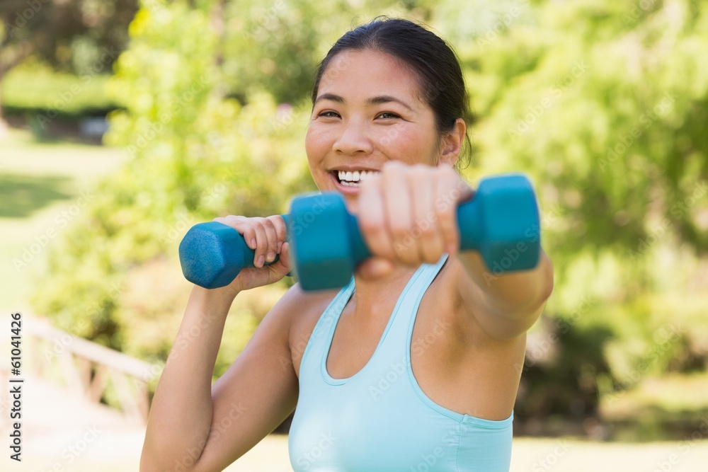 Healthy smiling woman exercising with dumbbells in park Healthy smiling woman exercising with dumbbells in park