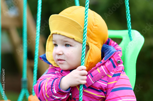 Portrait of cute toddler girl in multicolor coat and orange hat