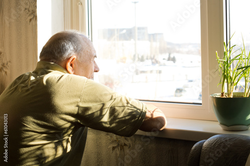 Obraz na płótnie Lonely old man staring out of a window w salonie