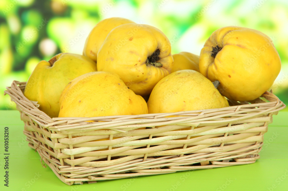 Sweet quinces in wicker basket on table on bright background