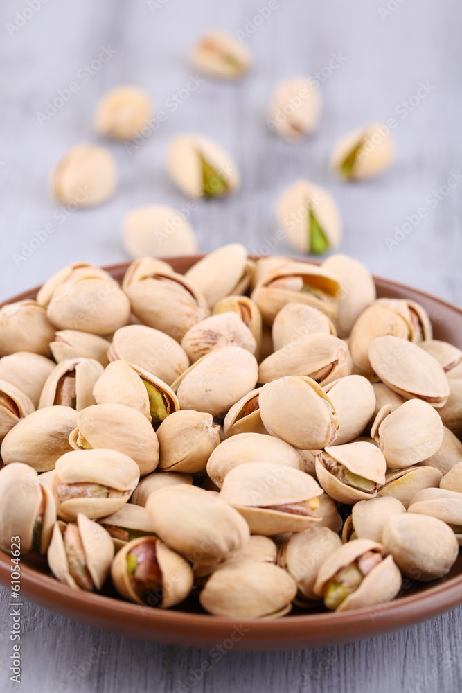 Pistachio nuts on plate on wooden background Pistachio nuts on plate on wooden background