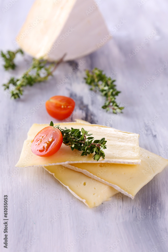 Tasty Camembert cheese with thyme and tomato, on wooden table Tasty Camembert cheese with thyme and tomato, on wooden table
