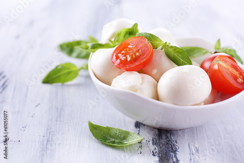 Tasty mozzarella cheese with basil and tomatoes in bowl,