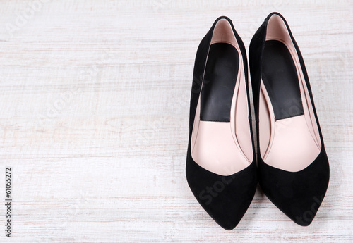 Beautiful black female shoes on wooden background