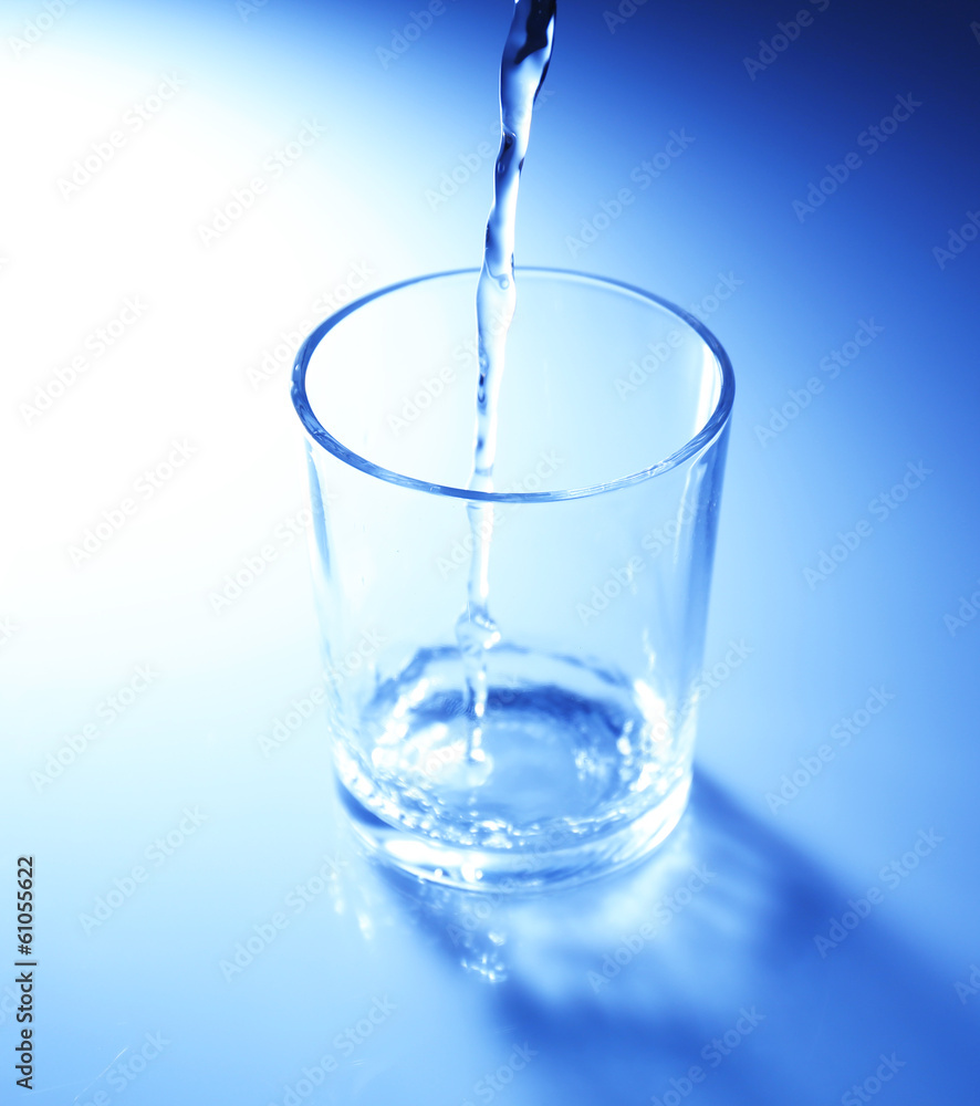 Pour water from pitcher into glass, on dark blue background Pour water from pitcher into glass, on dark blue background