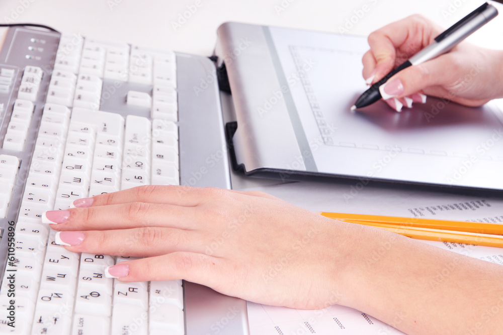 Female hand using graphics tablet on table close up Female hand using graphics tablet on table close up