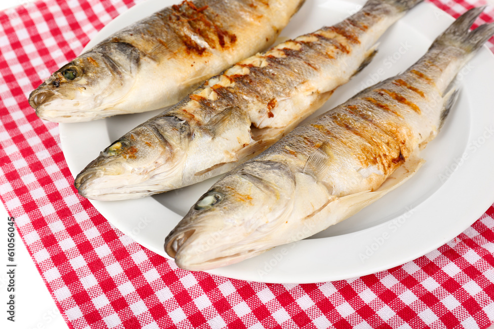 Delicious grilled fish on plate on table close-up Delicious grilled fish on plate on table close-up