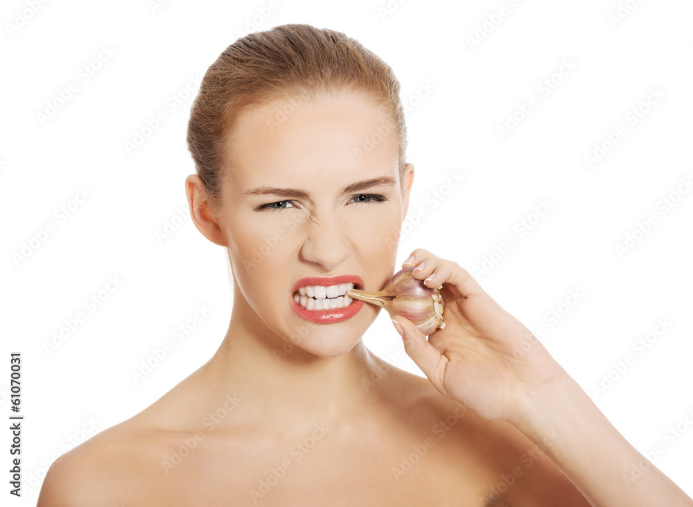 Beautiful caucasian topless woman with raw garlic in mouth. Beautiful caucasian topless woman with raw garlic in mouth.