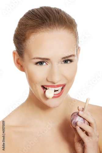 Beautiful caucasian topless woman with raw garlic in mouth.