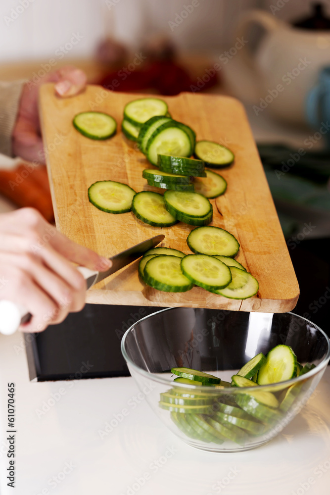 Caucasian attractive young woman is cutting cucumber. Caucasian attractive young woman is cutting cucumber.