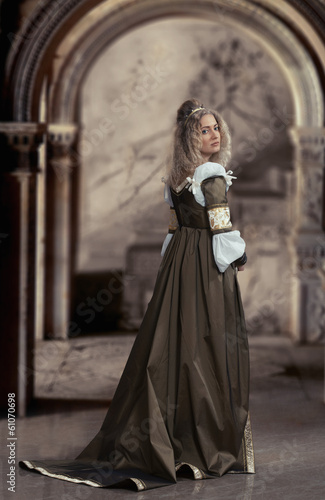 Woman in medieval dress looking back, antique interior © rodjulian