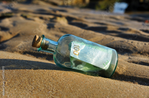 Money in the bottle on the beach photo