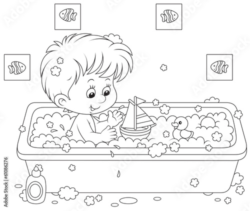 Little boy playing with toys in a bath with foam