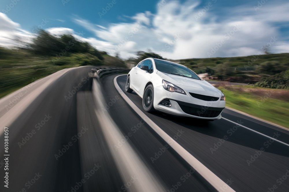 Fototapeta premium White car cornering in mountain road with speed blur