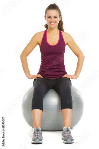 Smiling fitness young woman sitting on fitness ball