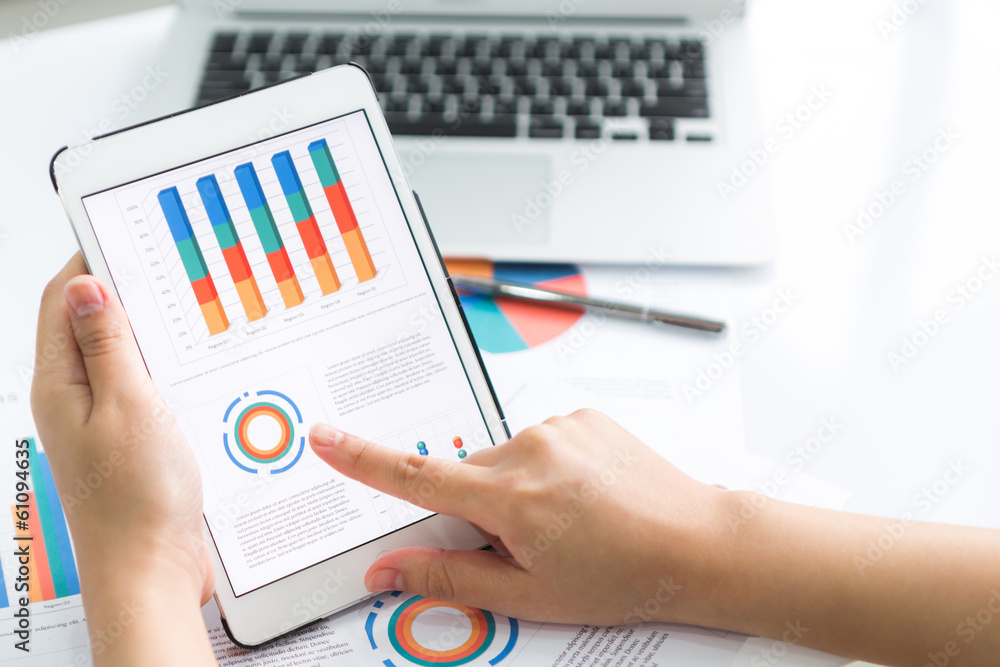 Close-up of business person using digital tablet with financial Close-up of business person using digital tablet with financial