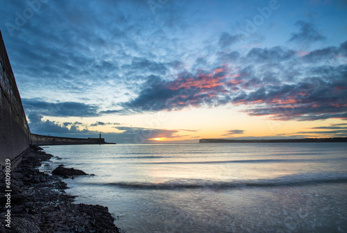 Beautiful vibrant sunrise sky over calm water ocean with lightho photo