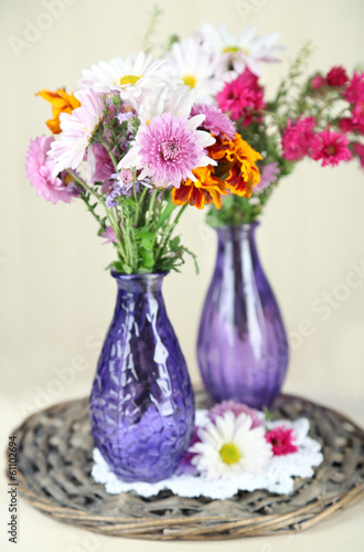 Wildflowers in glass vases on table on wooden background