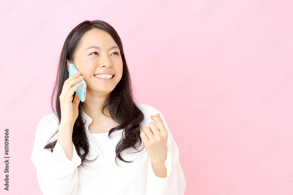 スマートフォンで話す女性・ピンクバック